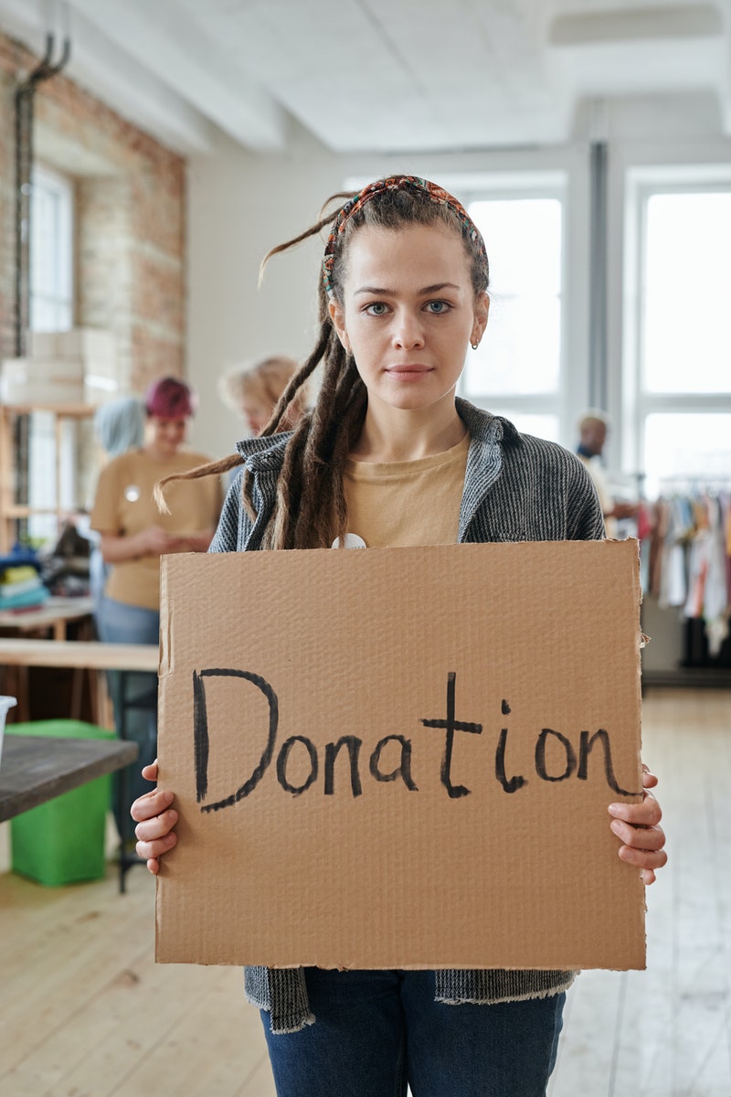 A Woman Holding a Cardboard with Inscription